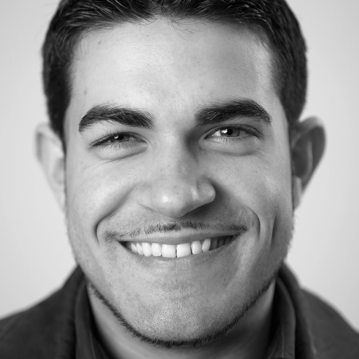 Watson Fellow Oscar Baez smiles at the camera, black and white, head only