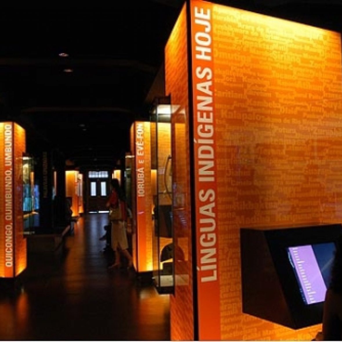 exhibit at the Museum of the Portuguese Language in Brazil, in a dark room with orange walls with writing on them about language history