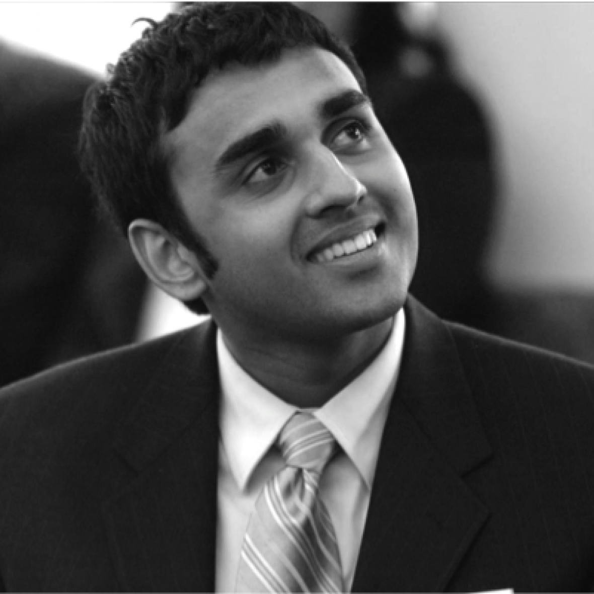 Watson Fellow Reggie Thomas smiles towards the upper right, wearing a suit and tie, in black and white