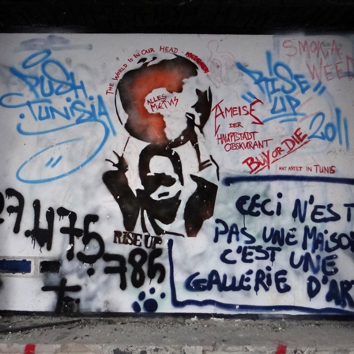 graffiti on a wall in Ghana of text written in French, shadow of a young Black child holding up the globe, and other words/numbers